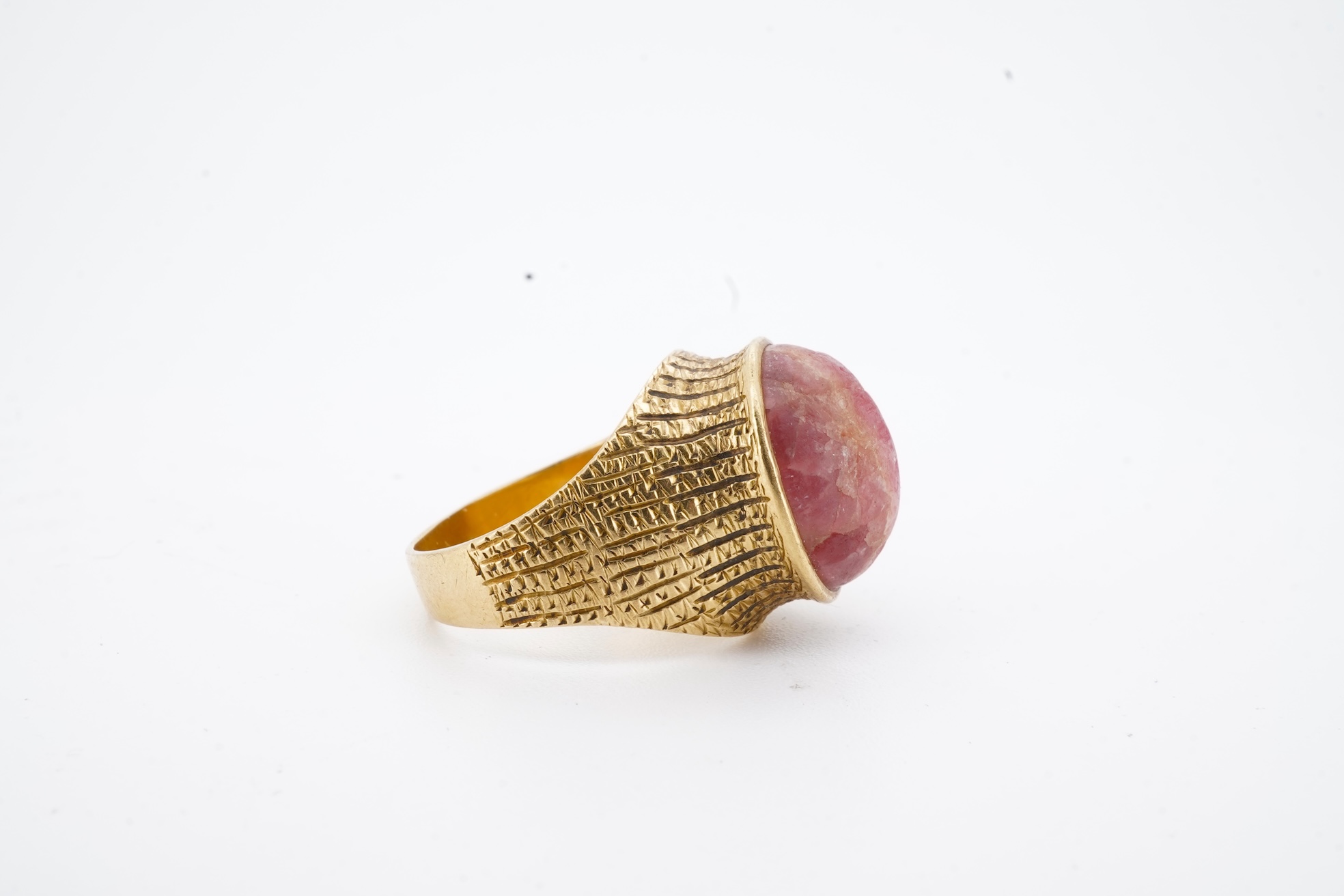 A continental textured yellow metal and cabochon rose quartz set ring, size N/O, gross weight 8.2 grams.